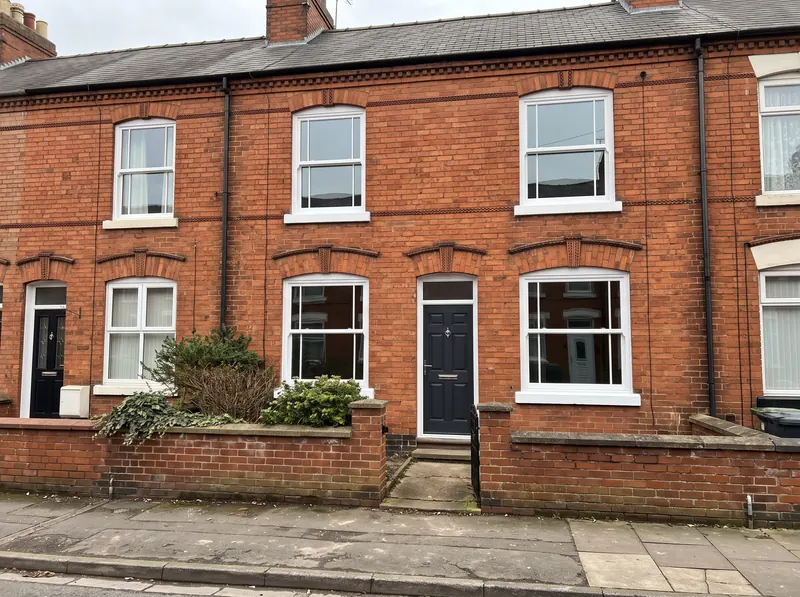 Red-brick Victorian terraced house in Leicester with white uPVC sash-style windows and a dark composite front door